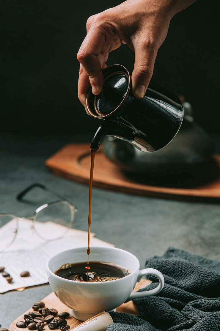 close-up-hand-pouring-coffee-water-into-coffee-cup-international-coffee-day-concept_1150-25432